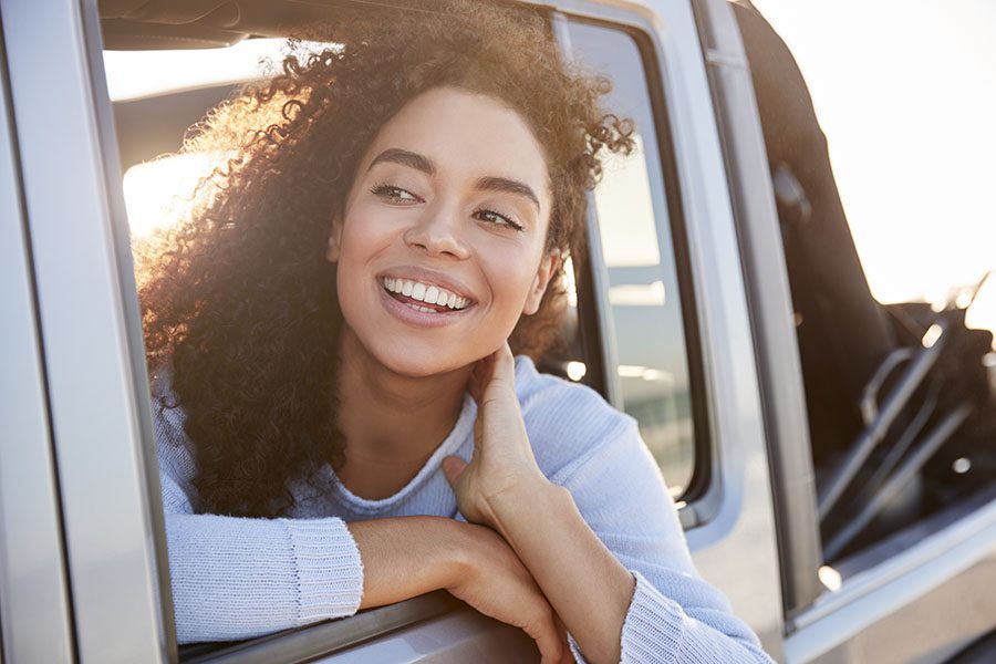 Contact - Portrait of a Young Smiling Woman Sitting in a Car Sticking Her Head Out the Window to Look Around