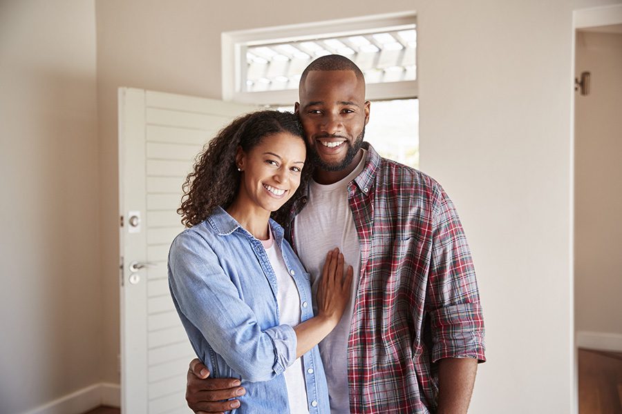 Insurance Quote - Portrait of a Cheerful Young Married Couple Standing Inside Their New Home